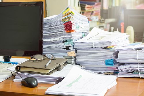 Pile of unfinished documents on office desk