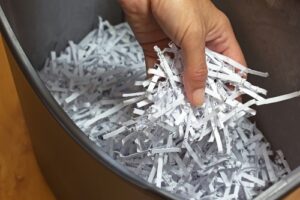 Hand holding shredded paper strips in a basket shredders
