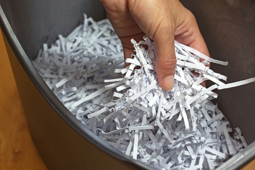 Hand holding shredded paper strips in a basket shredders