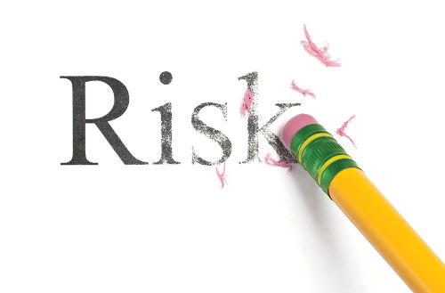 Close up of a yellow pencil erasing the word Risk.