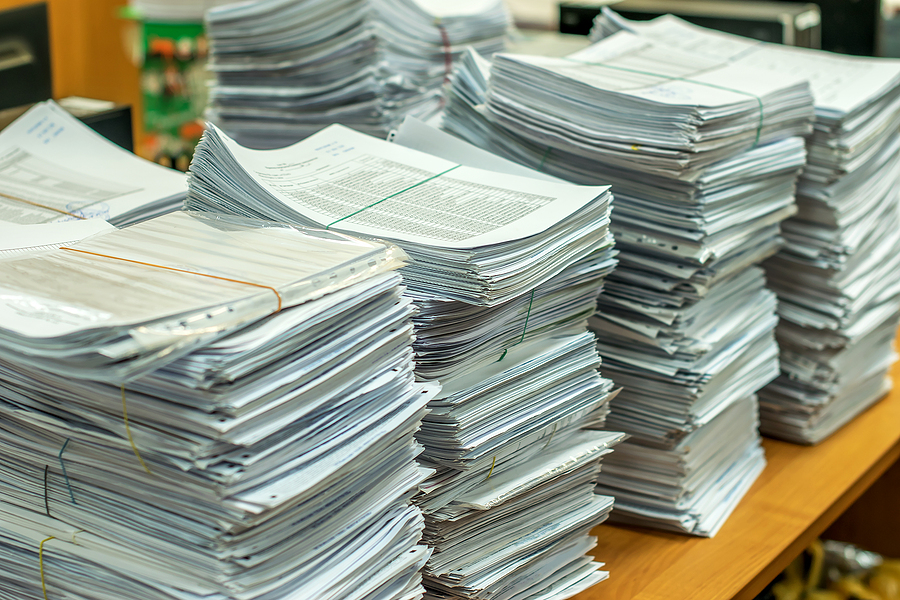 Stacks of paper documents on a work table in an office