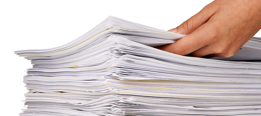 A hand adding more files to a large stack of documents
