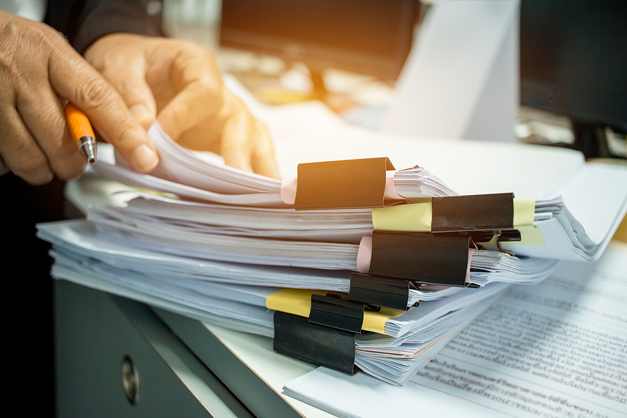 A person's hands working on Stacks of documents.